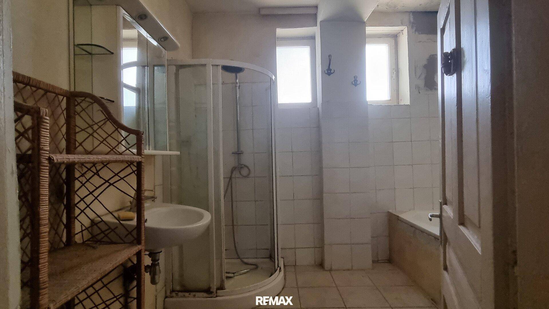 Badezimmer mit Duschkabine, Waschbecken und Badewanne, das eine Modernisierung benötigt.