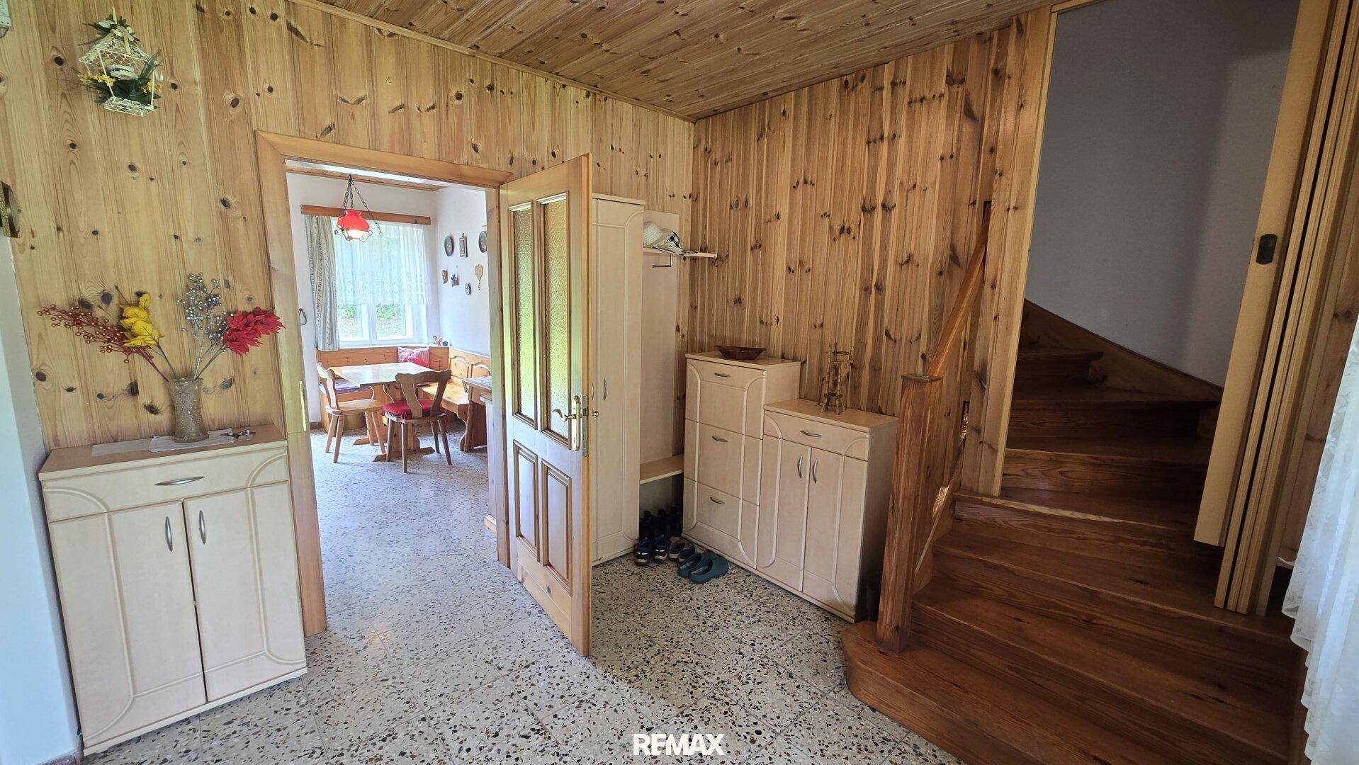 Eingangsbereich mit Holztreppe, Holztäfelung und Zugang zum Essbereich.