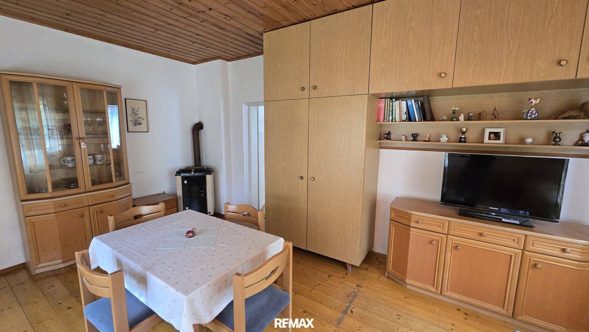 Wohnzimmer mit Esstisch, Holzschrankwand und Kaminofen.