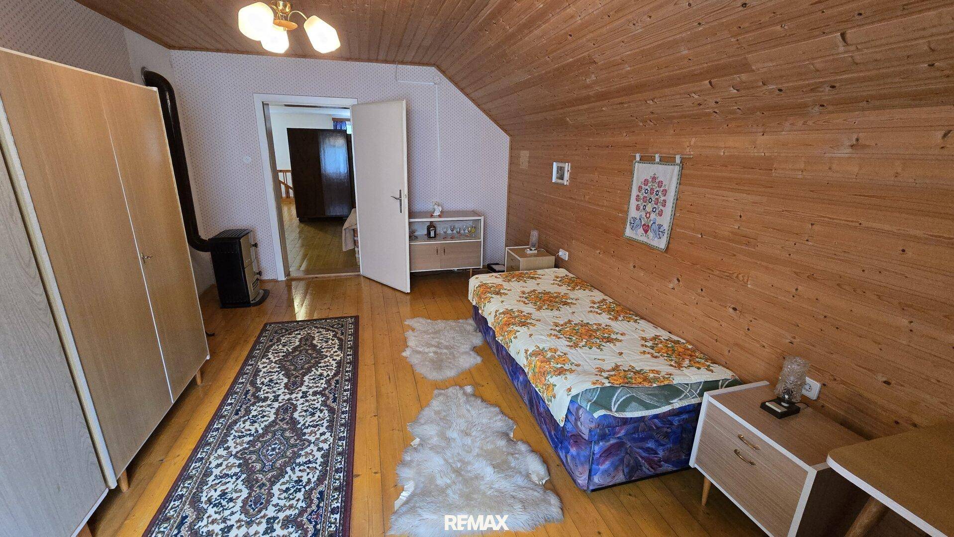 Schlafzimmer mit Holzboden, Holzwänden und Dachschräge, bietet eine gemütliche Atmosphäre.