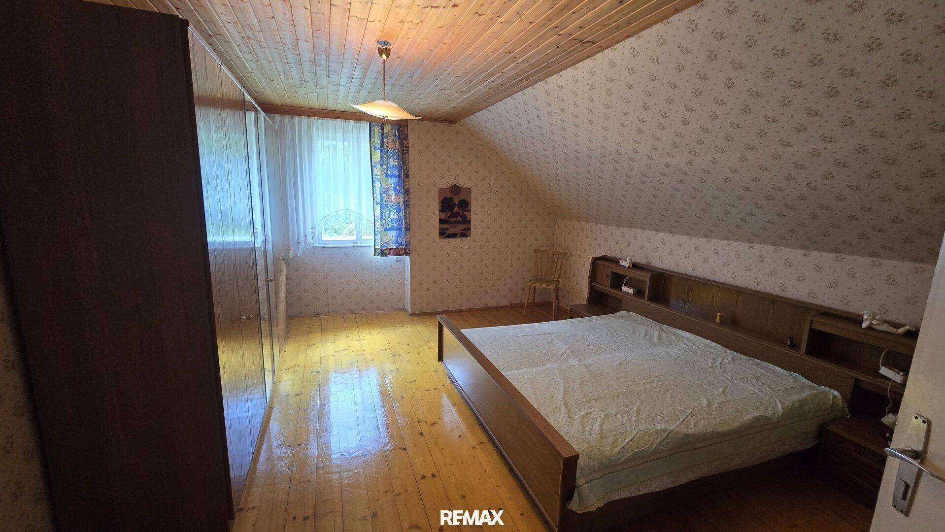 Gemütliches Schlafzimmer im Dachgeschoss mit Holzboden und Dachschräge.