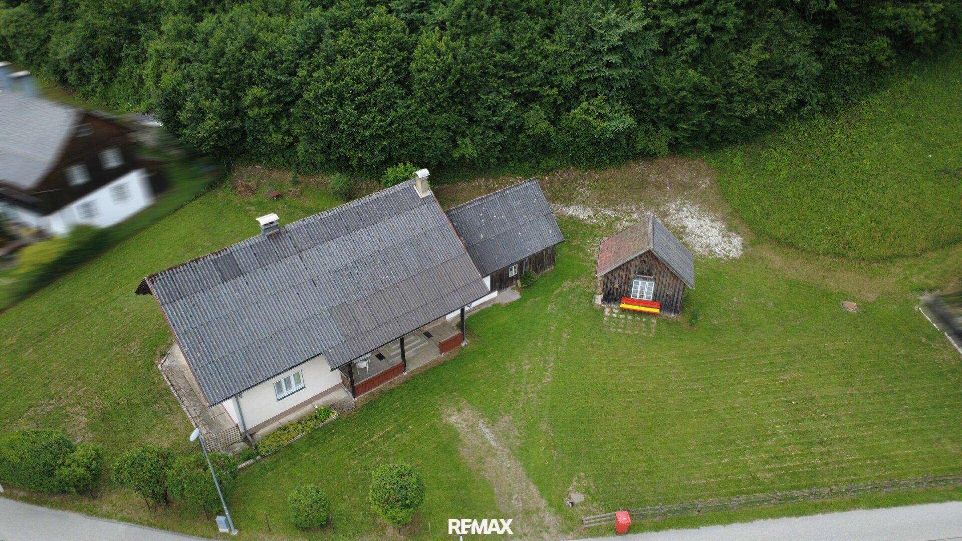 Luftaufnahme des Hauses mit Nebengebäude und großem Grundstück umgeben von Wald.