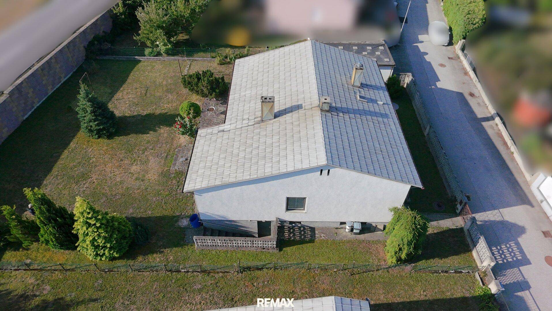 Luftaufnahme des Hauses von der Seite mit Dach und Gartenbereich.