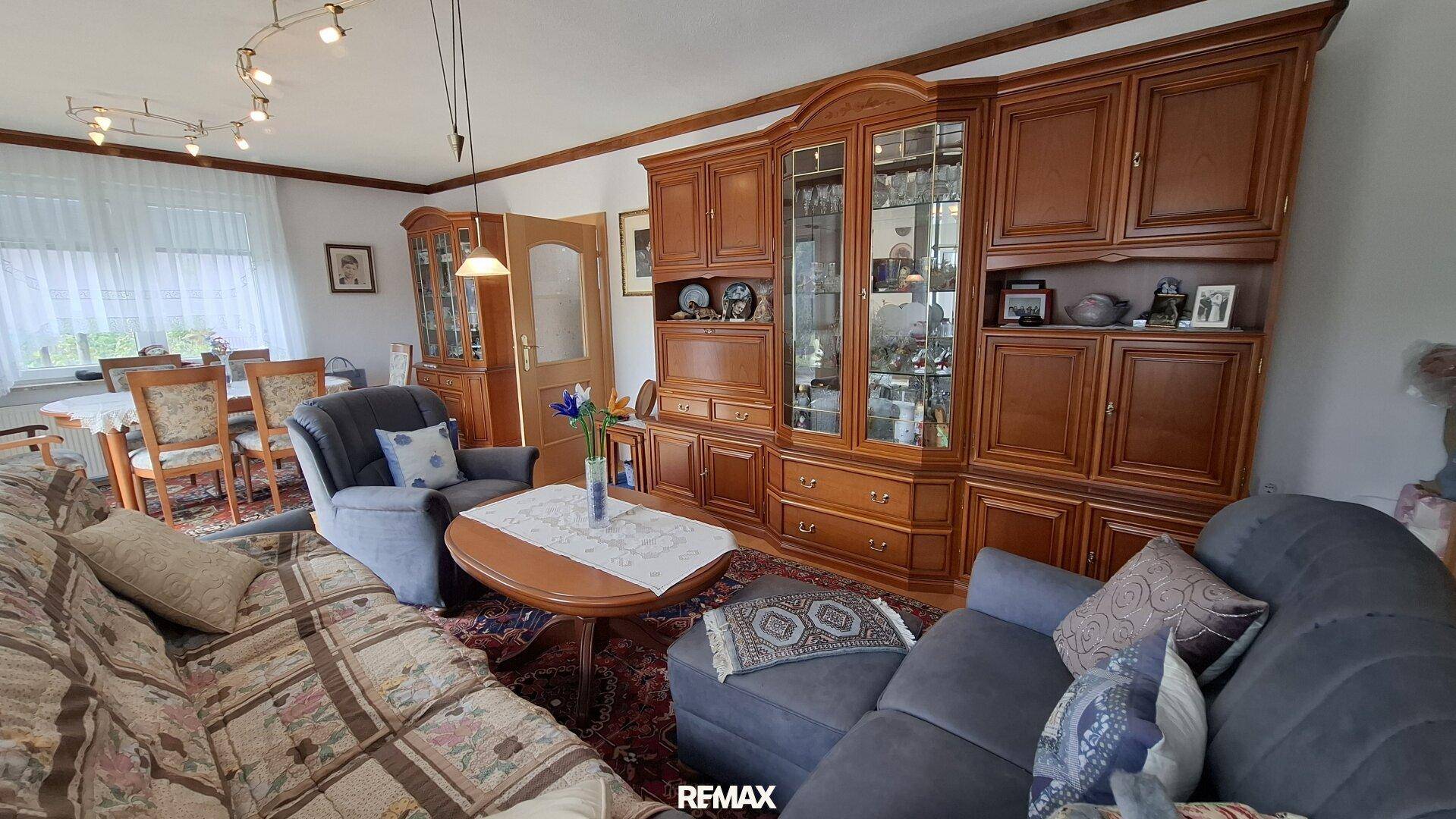 Gemütlicher Wohn- und Essbereich mit traditionellen Holzmöbeln und floral gemusterten Sofas.