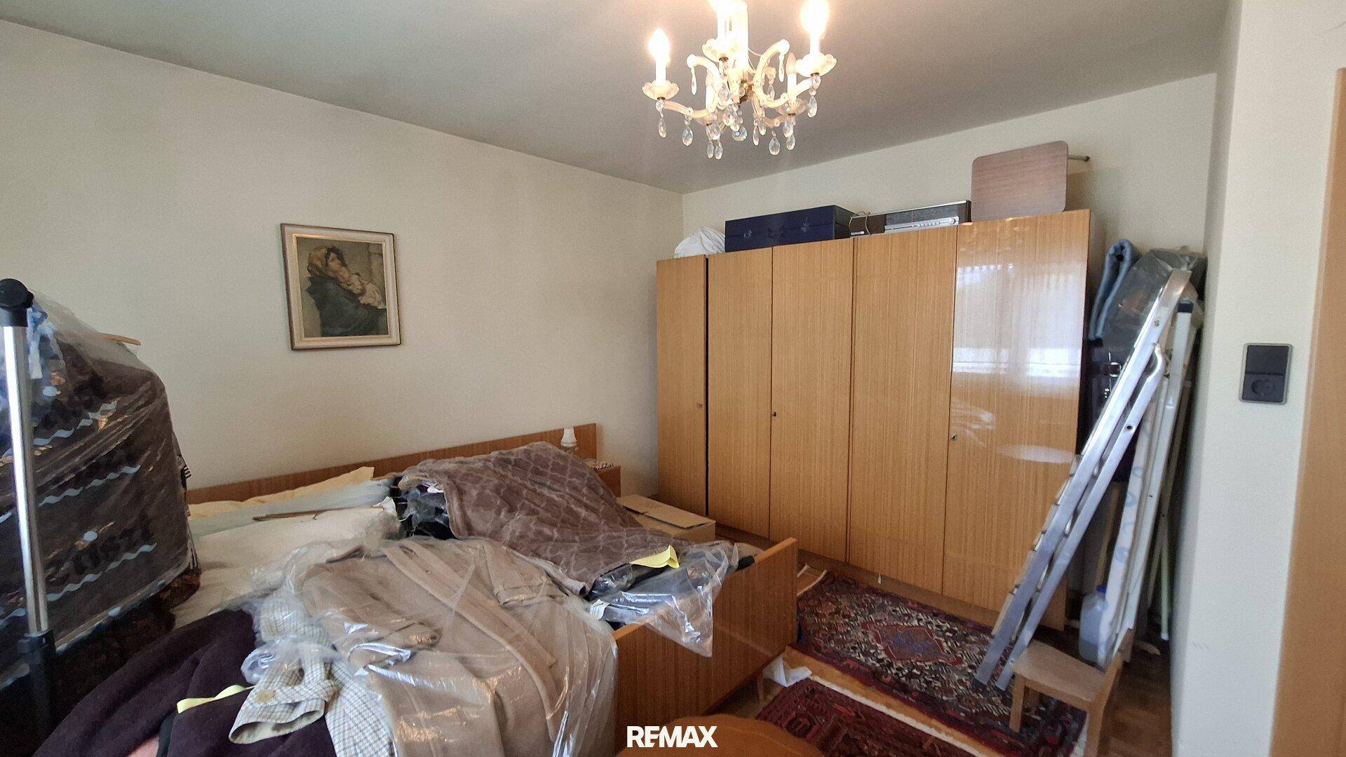 Schlafzimmer mit Holzkleiderschränken, einem Bett und einem klassischen Kronleuchter.