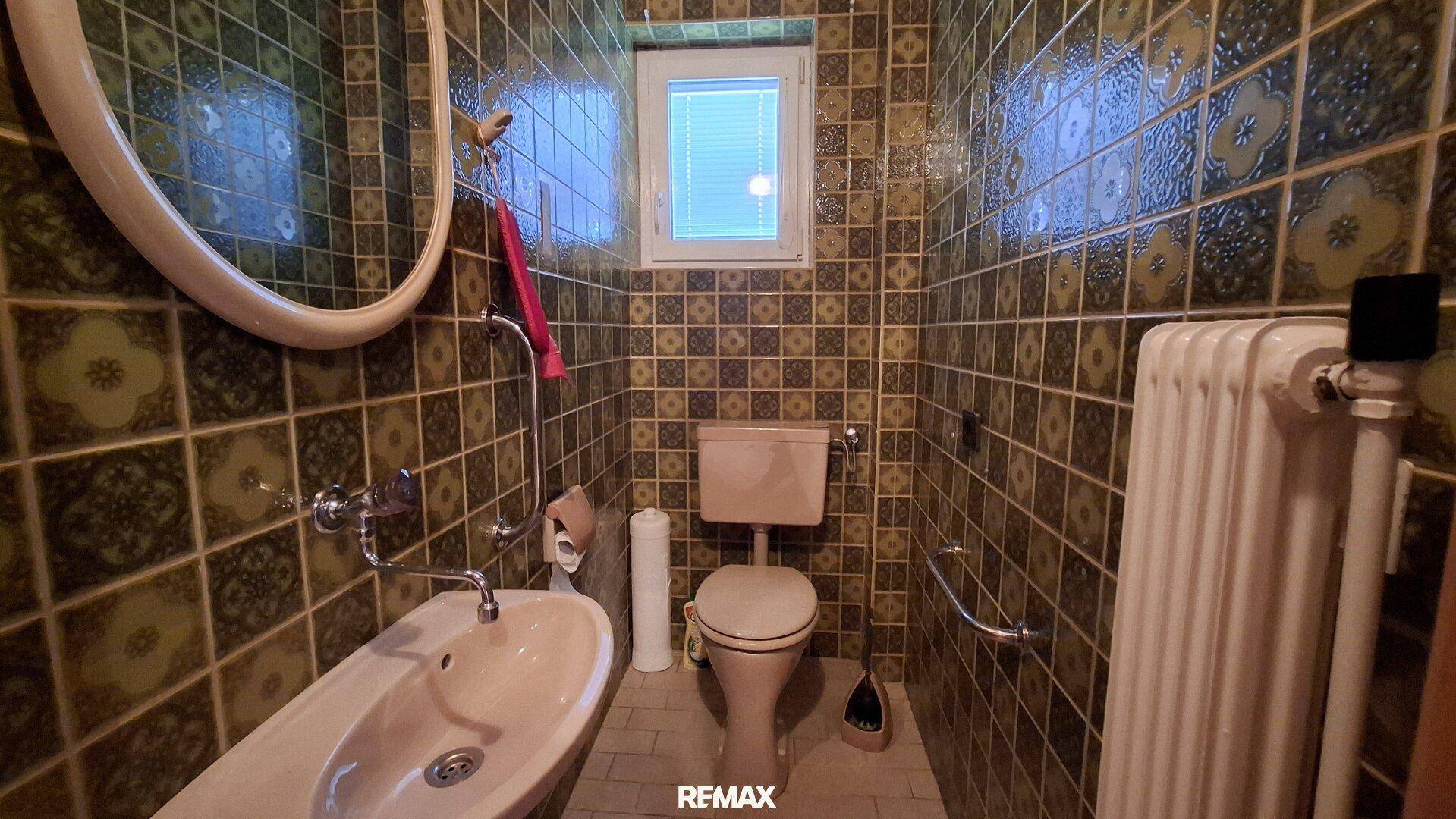 Separate Toilette mit Bidet, WC und grünen Fliesen im Retro-Stil.