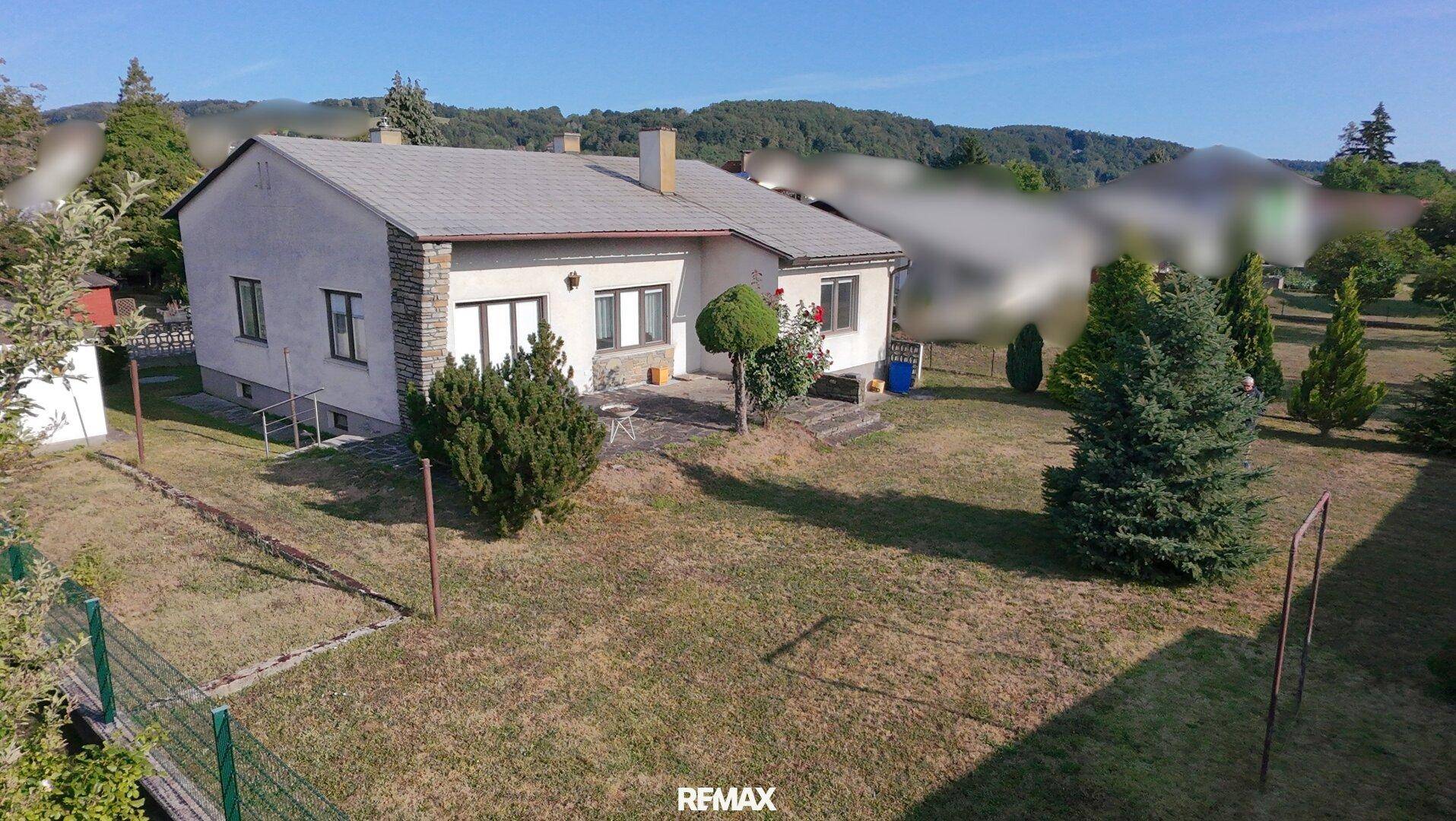 Luftaufnahme des Hauses von hinten mit großem Garten und Terrasse.