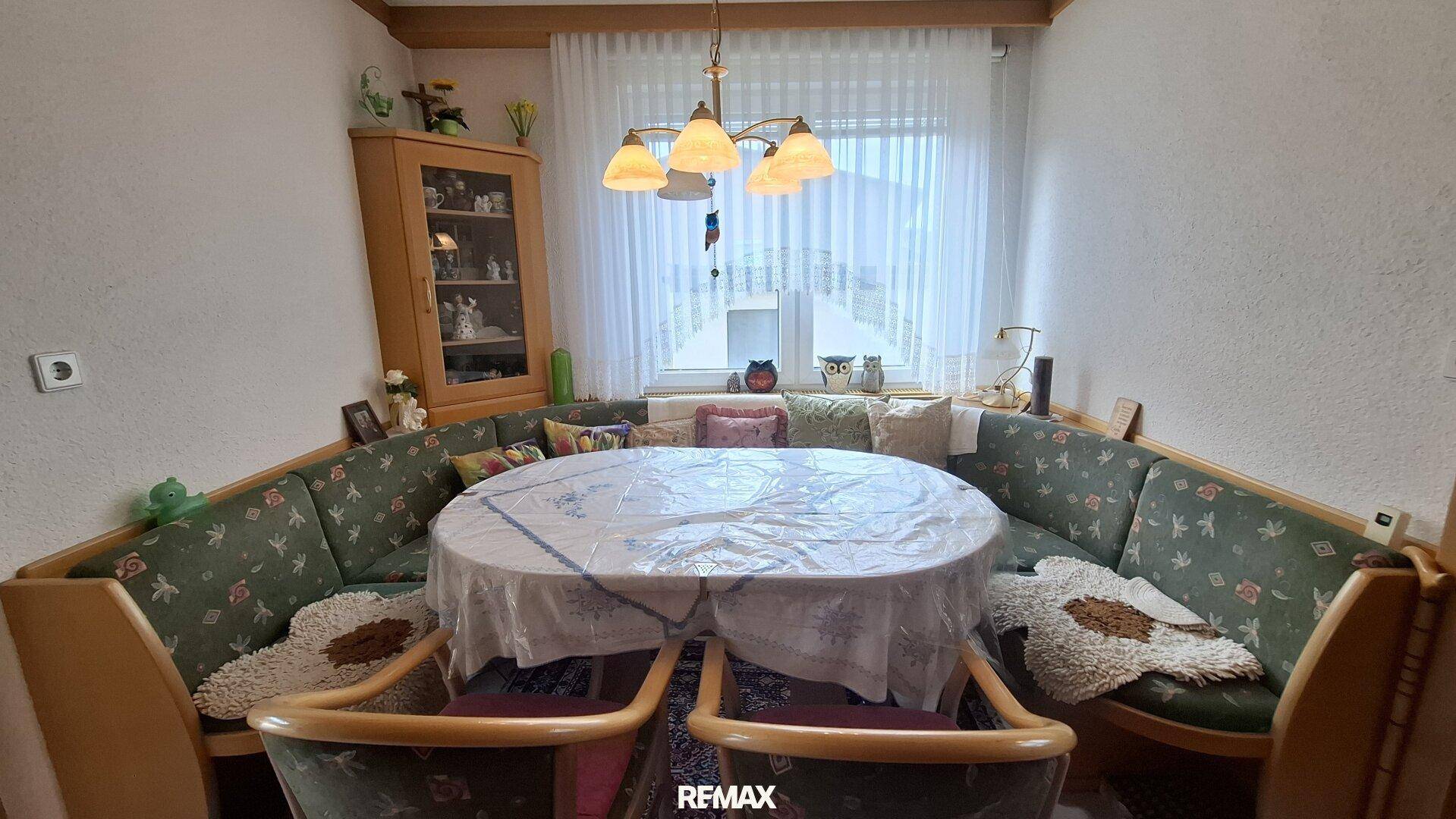 Gemütliche Essecke mit gepolsterten Sitzbänken, rundem Tisch und Fensterblick.