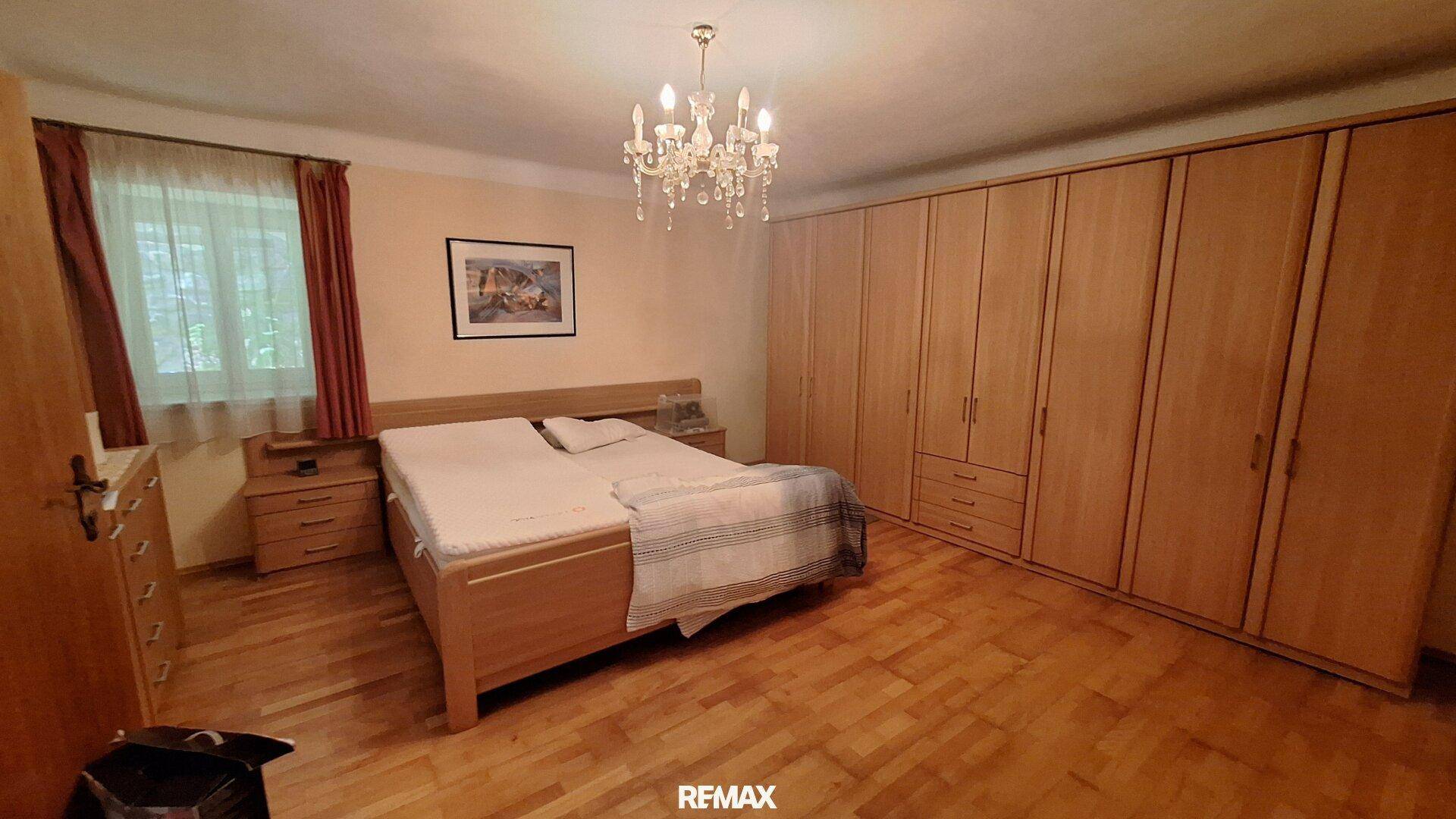 Schlafzimmer mit Doppelbett, Holzboden und großen Einbauschränken entlang einer Wand.