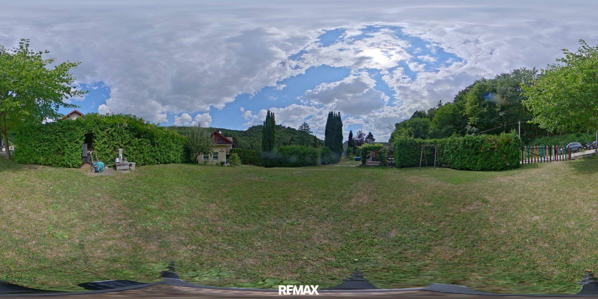 Weitläufige Rasenfläche mit Bäumen und Hecken, umgeben von ländlicher Landschaft.