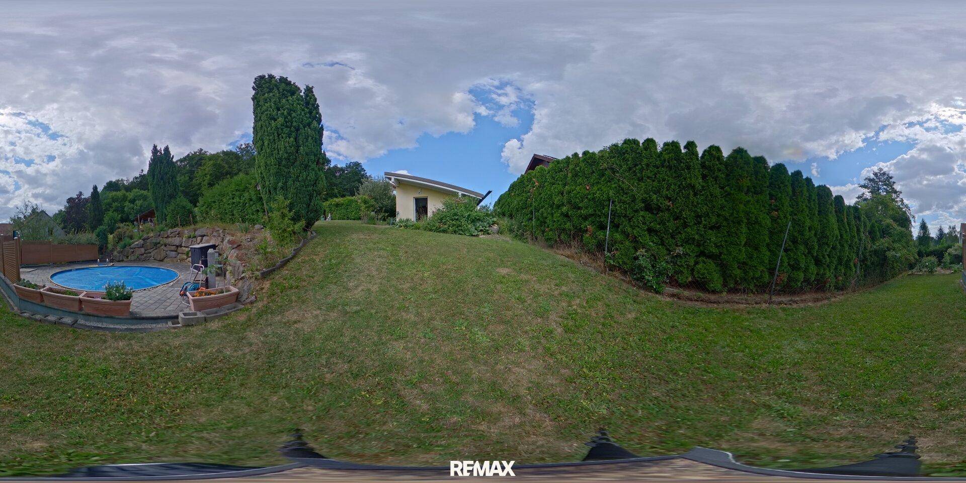 Panoramablick auf den Poolbereich und das Nebengebäude, umgeben von Grün.