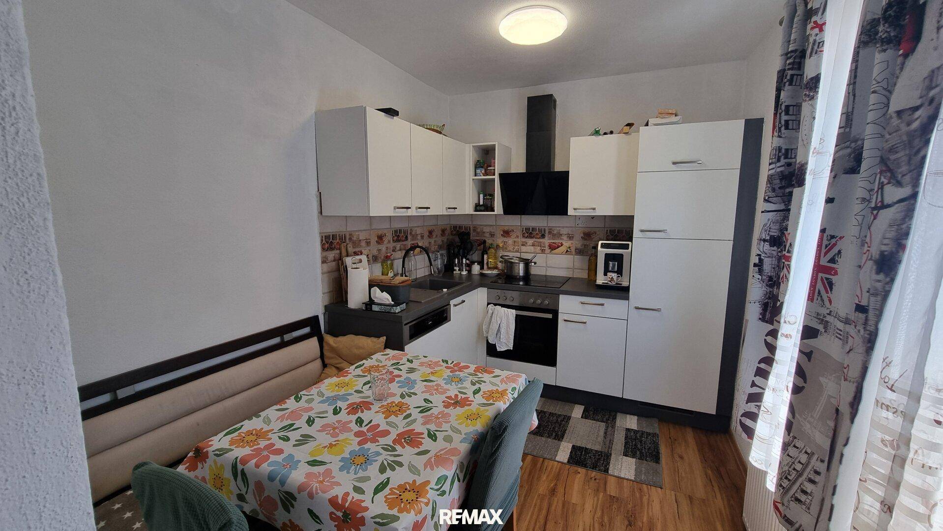 Funktionale Küche mit weißen Schränken, Essbereich und modernen Geräten, ideal für Familien.