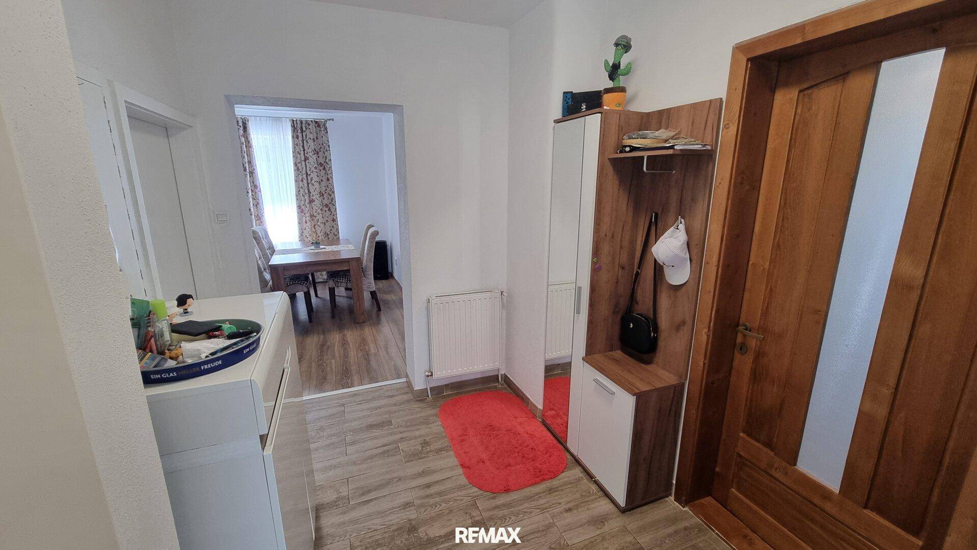 Heller Flur mit Holztür, Garderobe und Blick in den angrenzenden Essbereich.