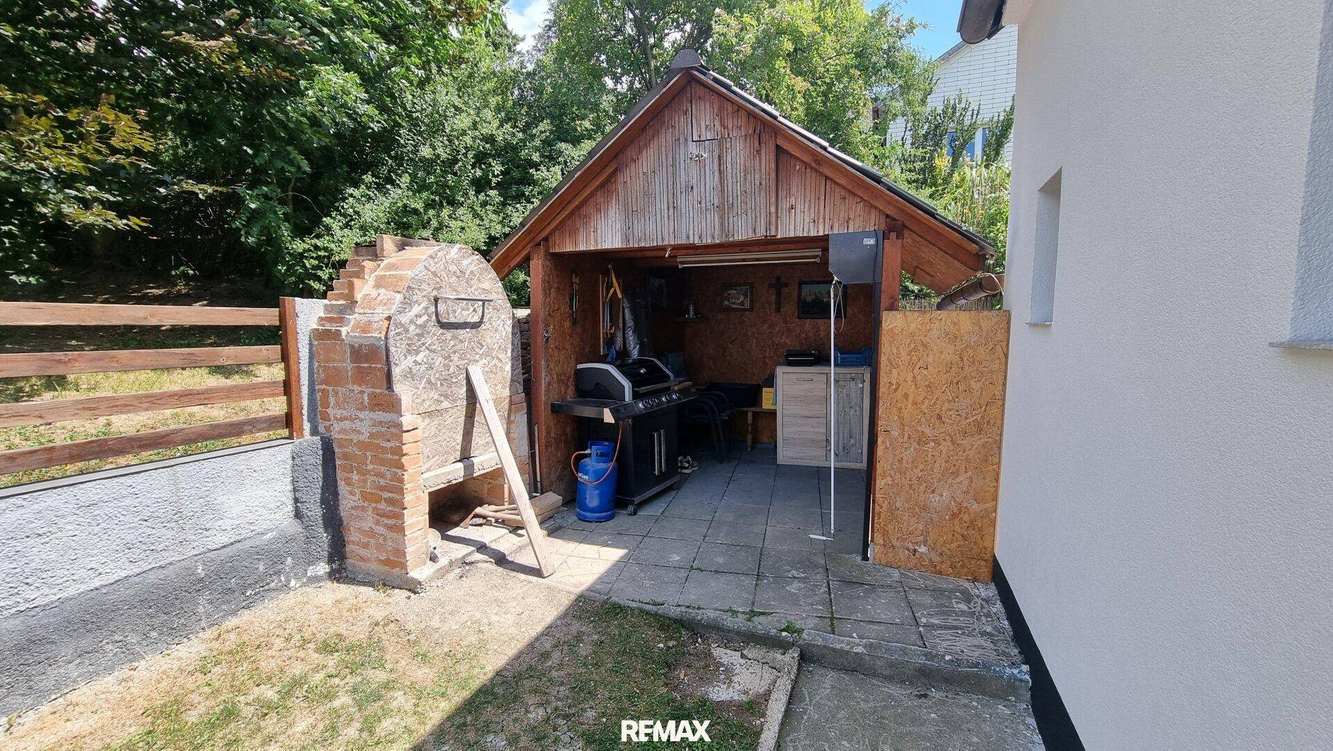 Überdachter Grillbereich im Freien mit gemauertem Grill und Platz für gesellige Stunden.