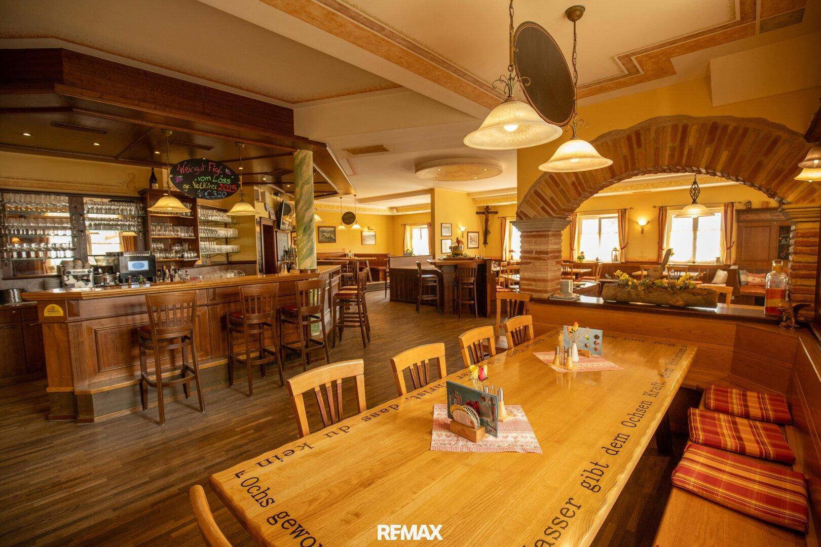 Gemütlicher Restaurantbereich mit Holztischen, Bänken und einer traditionellen Bar, die zum Verweilen einlädt.