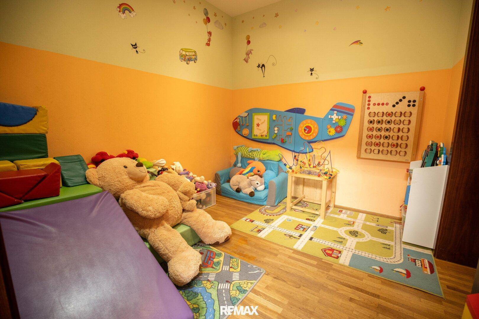 Buntes Spielzimmer für Kinder mit Matten, Plüschtieren und Wanddekorationen.