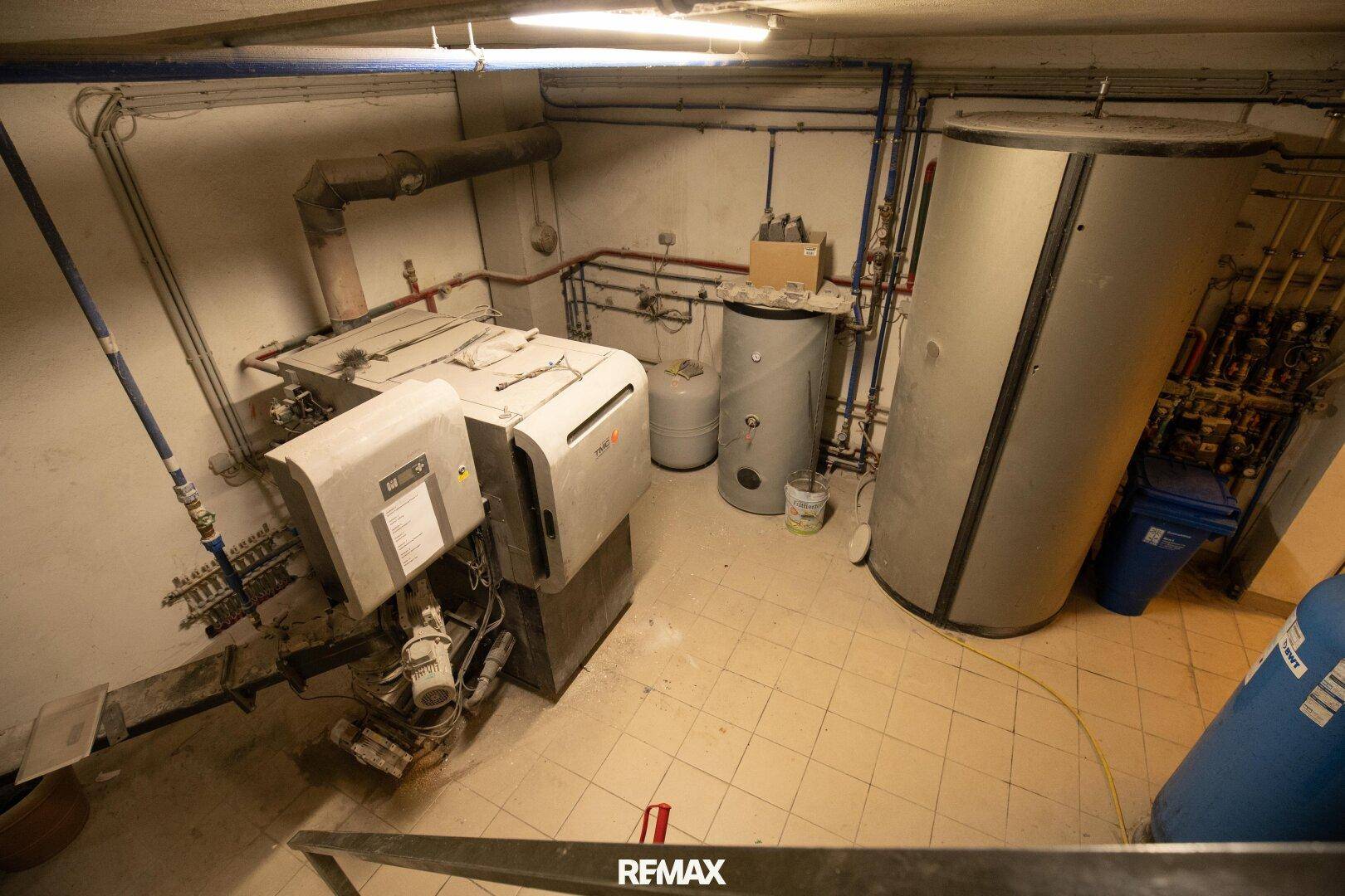 Heizungsraum mit Heizkessel, Warmwasserspeichern und komplexer Rohrleitungsinstallation für die Gebäudetechnik.