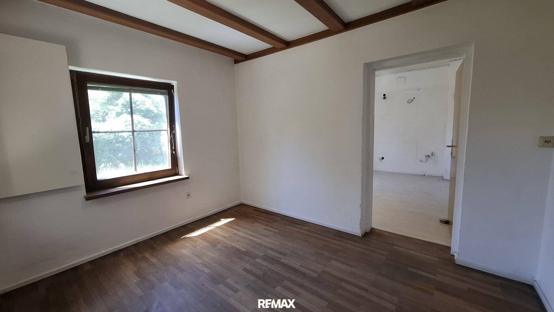 Gemütliches Zimmer mit Parkettboden und sichtbaren Holzdeckenbalken.