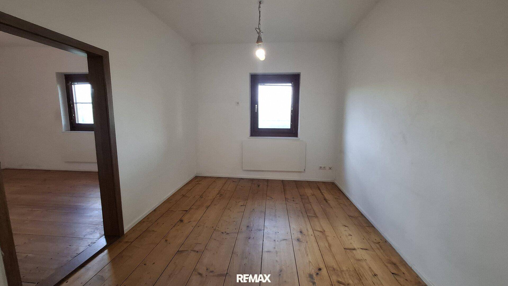 Geräumiges Zimmer mit hellem Holzplankenboden und Fenster.