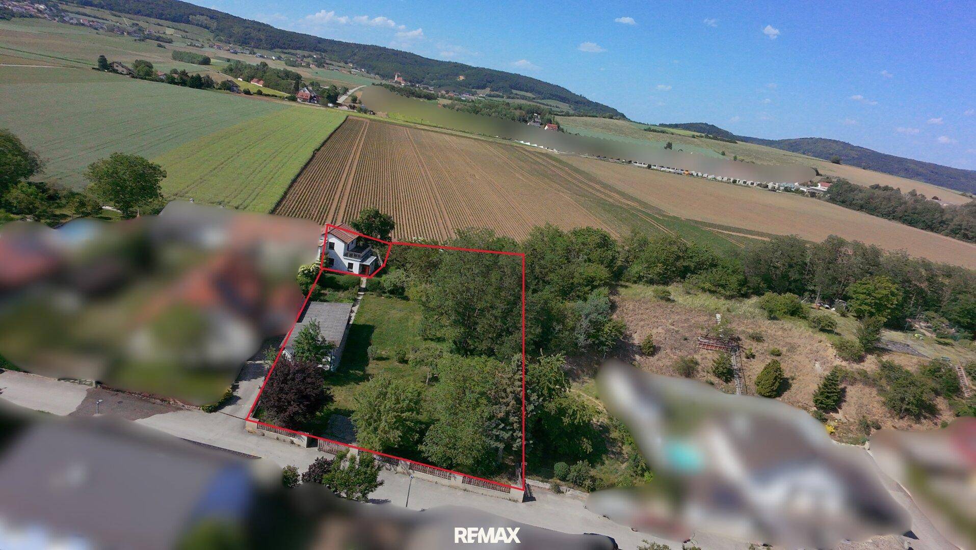 Luftaufnahme des Grundstücks mit markierten Grenzen und umliegender Landschaft.