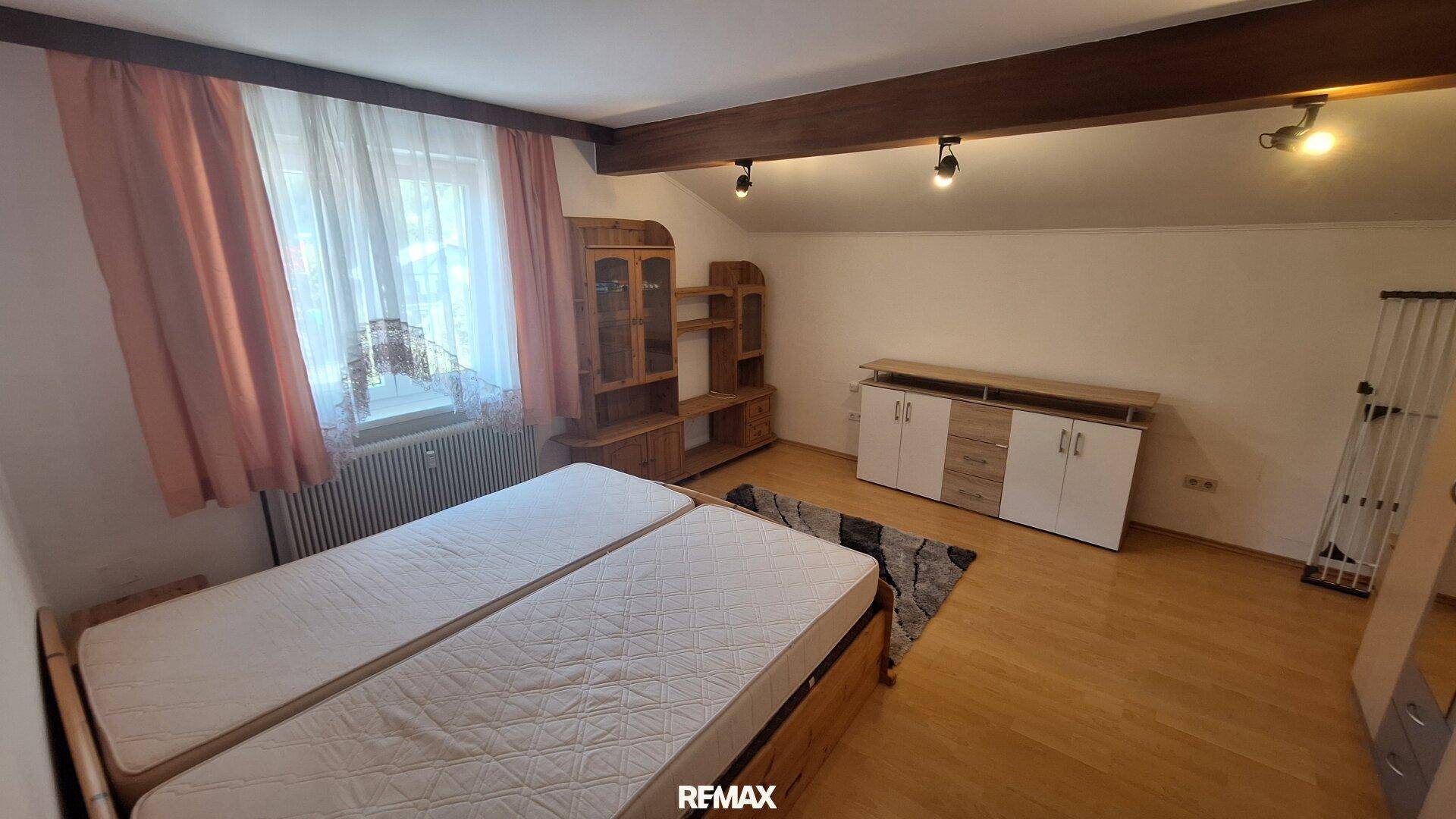Schlafzimmer im Dachgeschoss mit Holzbalken, Doppelbett und rustikalen Holzmöbeln.
