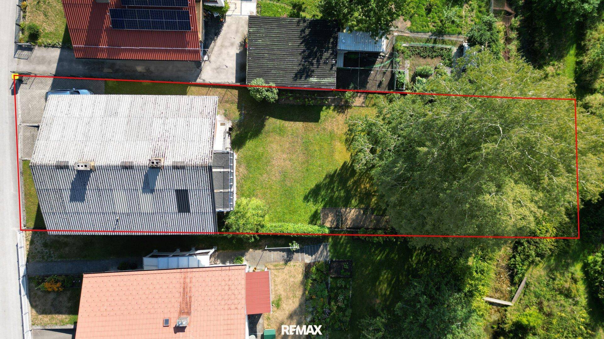 Luftaufnahme des Grundstücks mit großem Gartenbereich, umgeben von Bäumen und einer Straße.