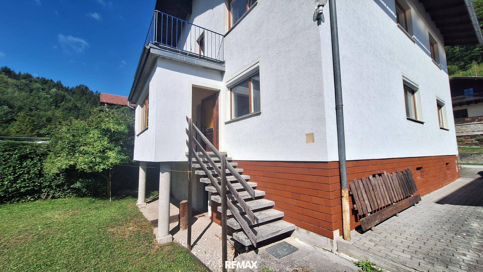 Seitenansicht des Hauses mit Außentreppe, Garten und Zugang zum oberen Stockwerk.