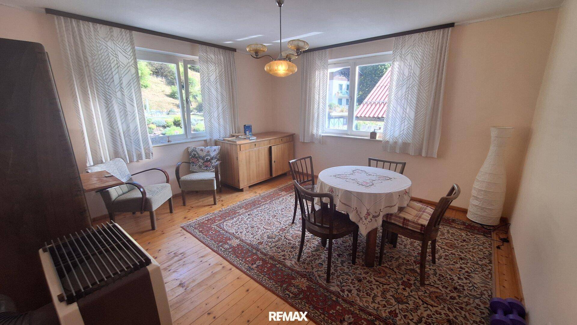 Gemütlicher Essbereich mit Holzboden, Esstisch und Fenstern mit Blick ins Grüne.