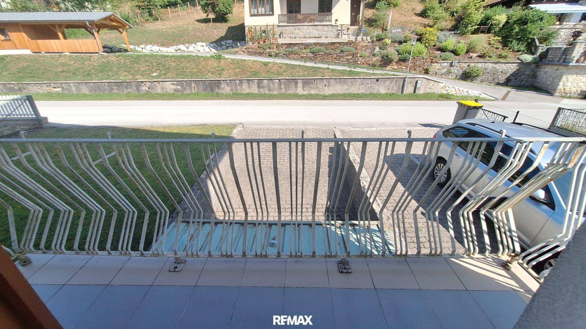 Balkon mit Metallgeländer und Blick auf die Straße und die gegenüberliegenden Hügel.