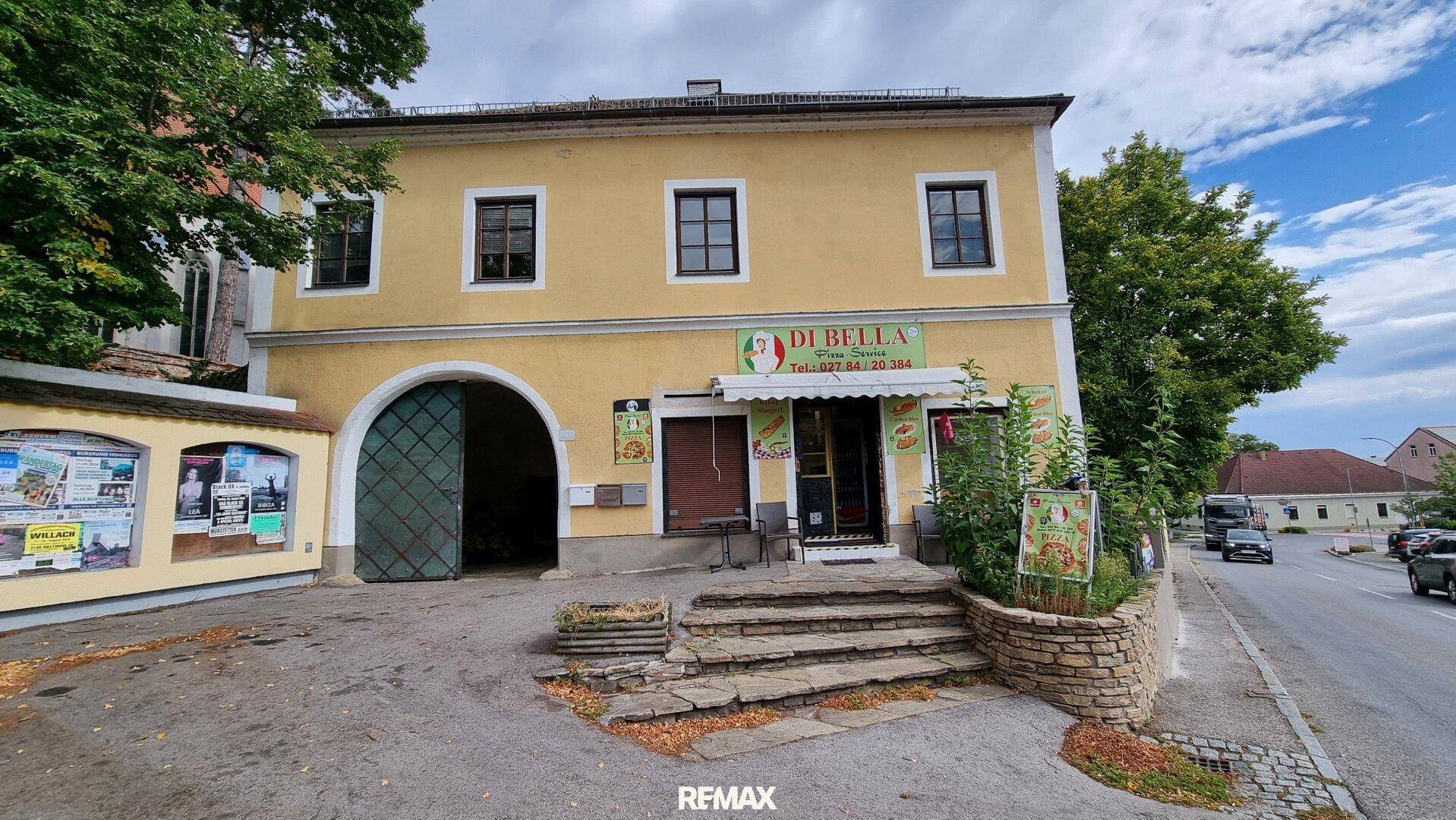 Vorderansicht des gelben Gebäudes mit Pizzeria im Erdgeschoss und traditionellen Fenstern.