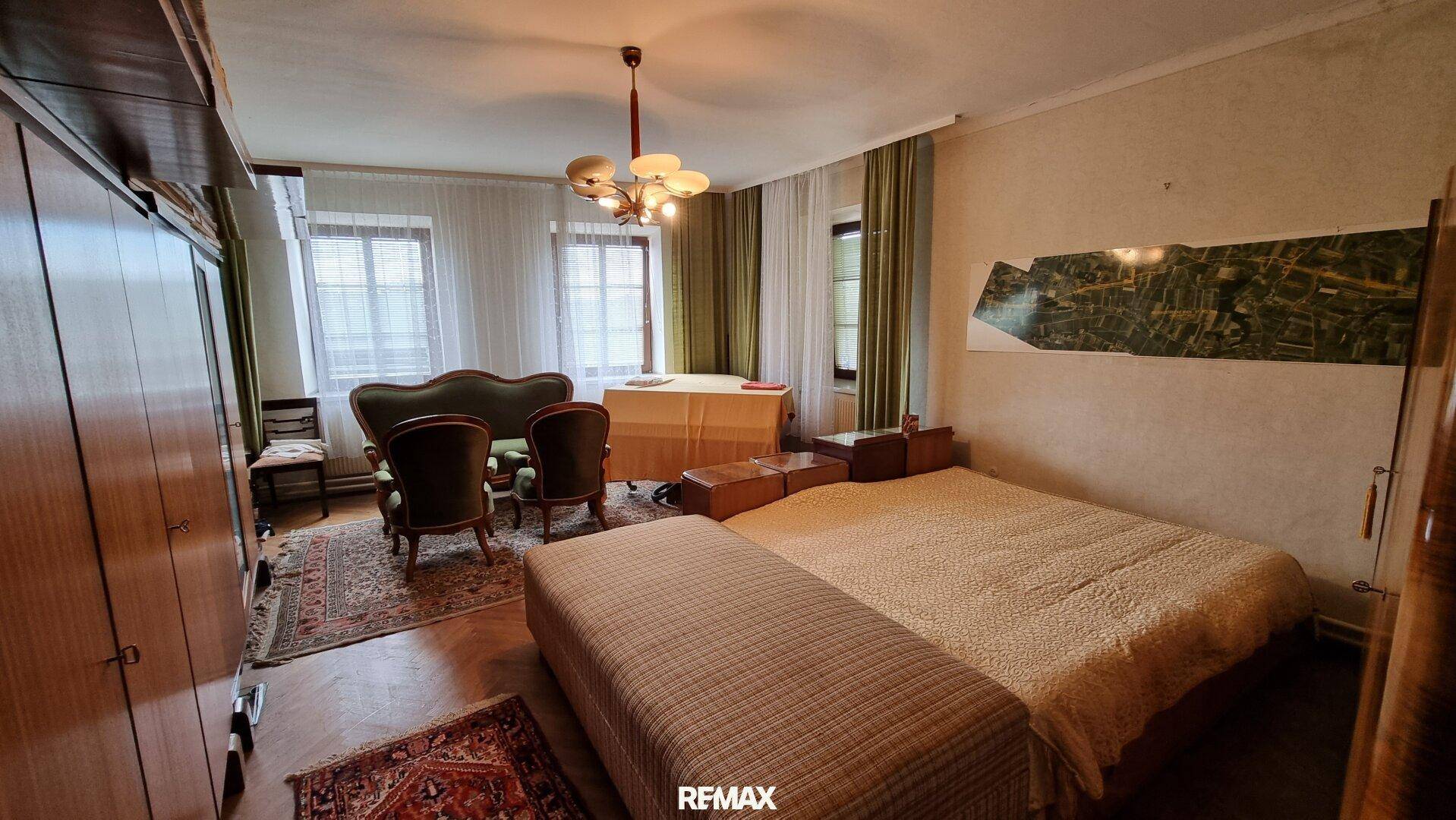 Schlafzimmer mit Doppelbett, traditionellen Möbeln und Blick auf die Umgebung durch die Fenster.