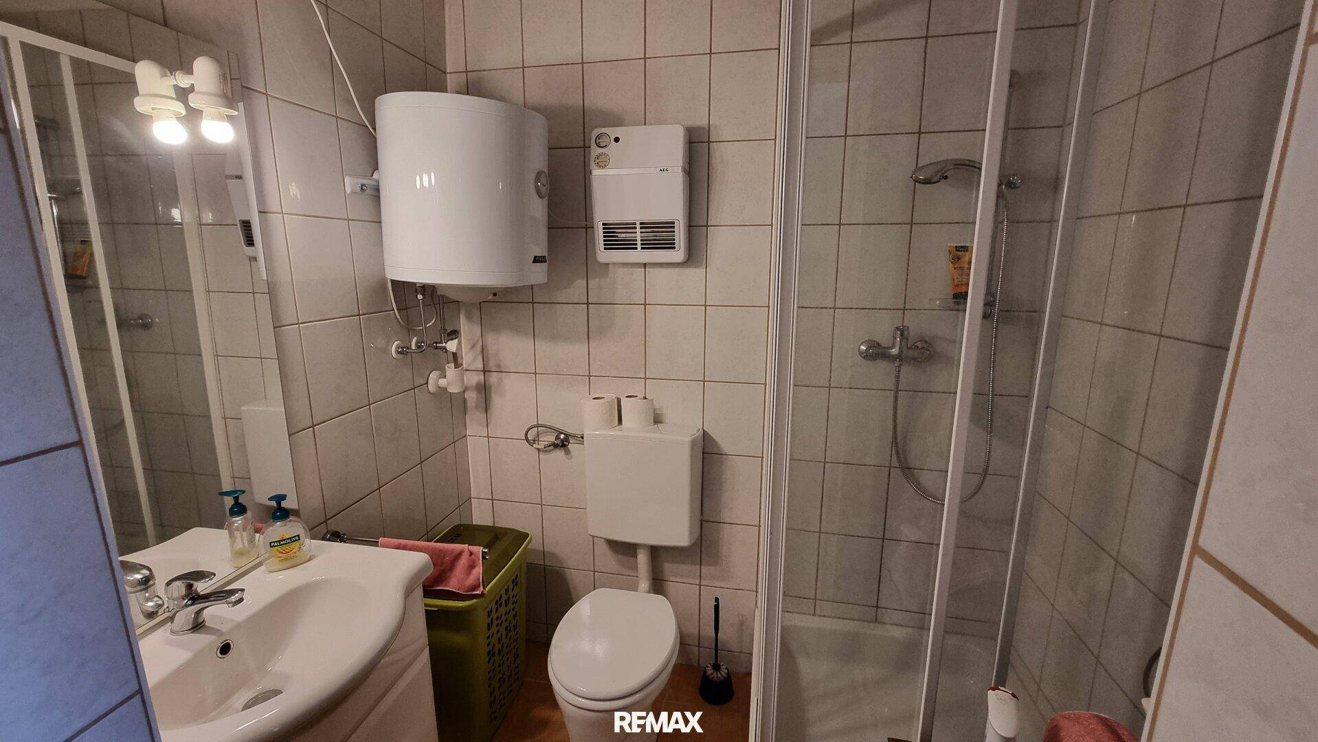 Modernisiertes Badezimmer mit Dusche, Toilette und Waschbecken, hell gefliest.