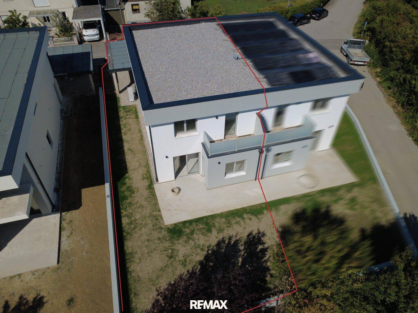 Luftaufnahme eines modernen Hauses mit Flachdach und umrandetem Grundstück.