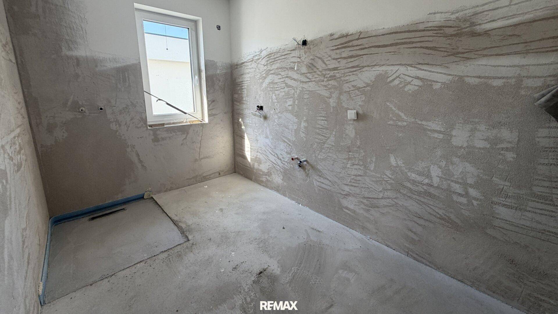 Unfertiges Badezimmer mit vorbereiteten Anschlüssen für Dusche oder Badewanne.
