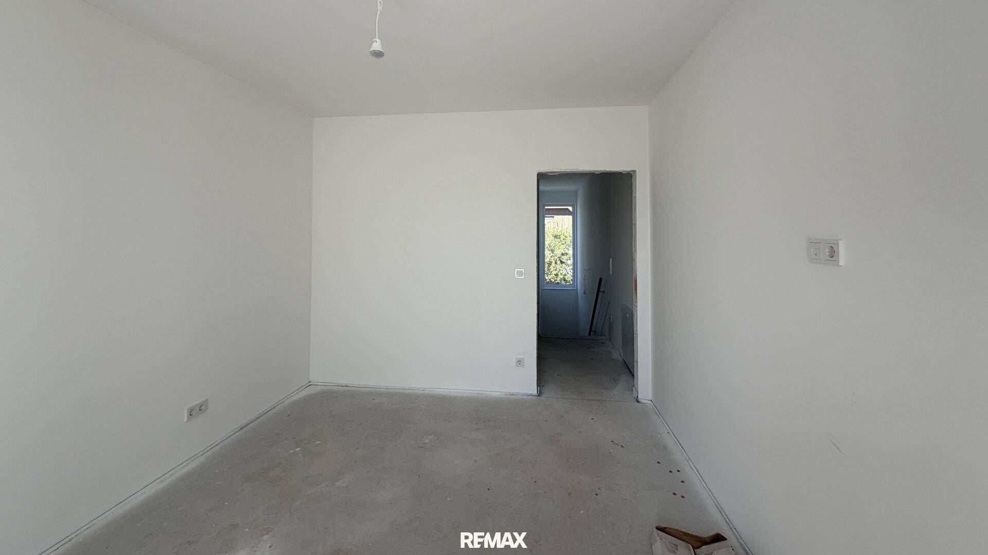 Unfertiges Zimmer mit Türöffnung zu einem weiteren Bereich, vielseitig nutzbar.