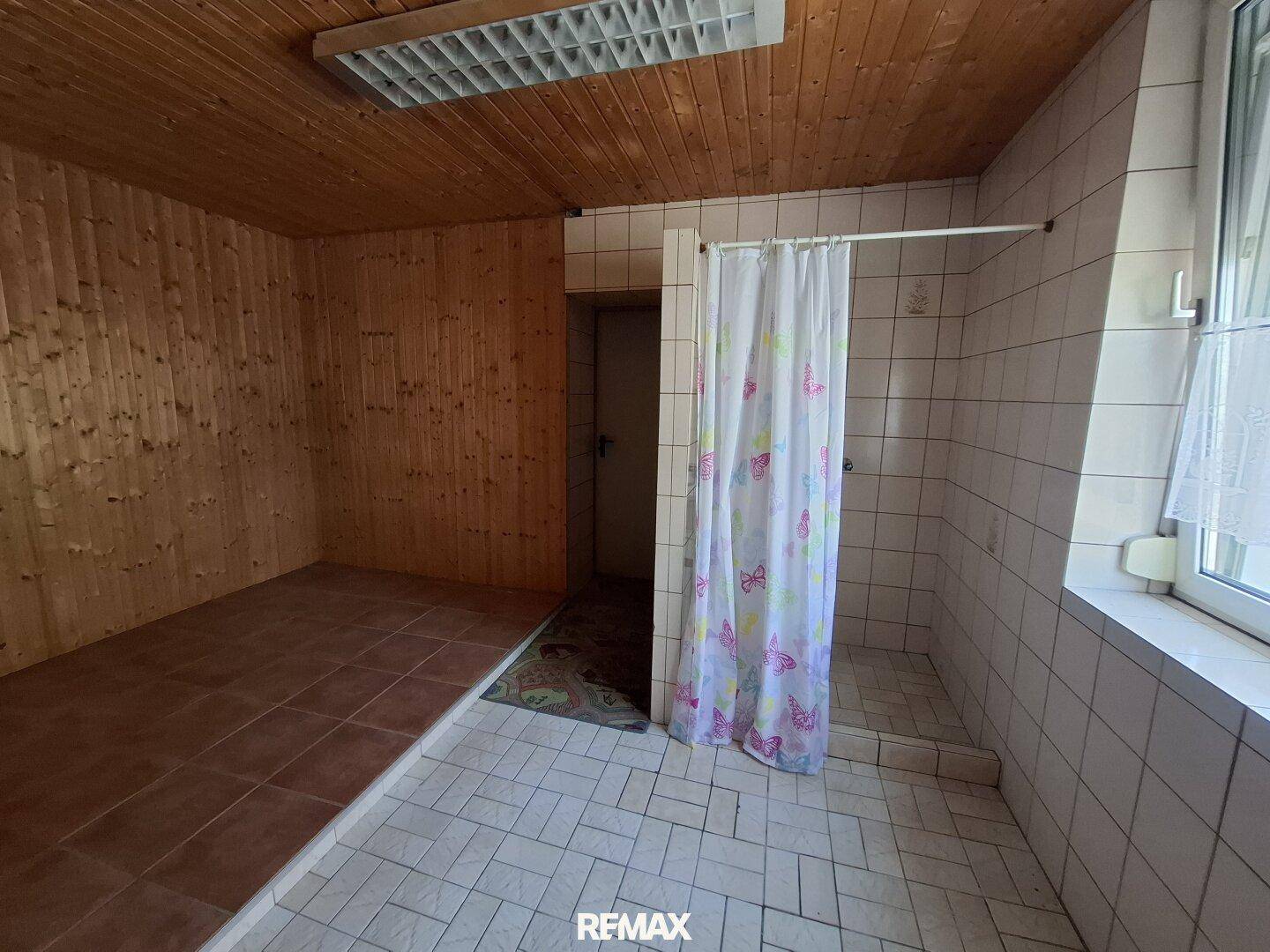 Badezimmer mit Duschbereich und angrenzender Holzsauna, ideal zur Entspannung.
