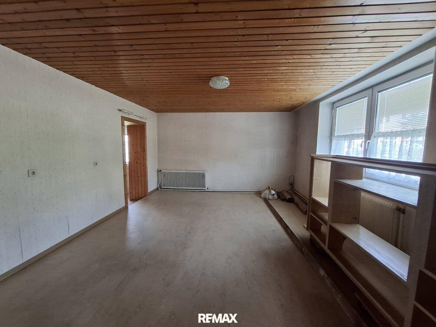 Schlafzimmer mit Holzdecke, Parkettboden und großem Fenster.