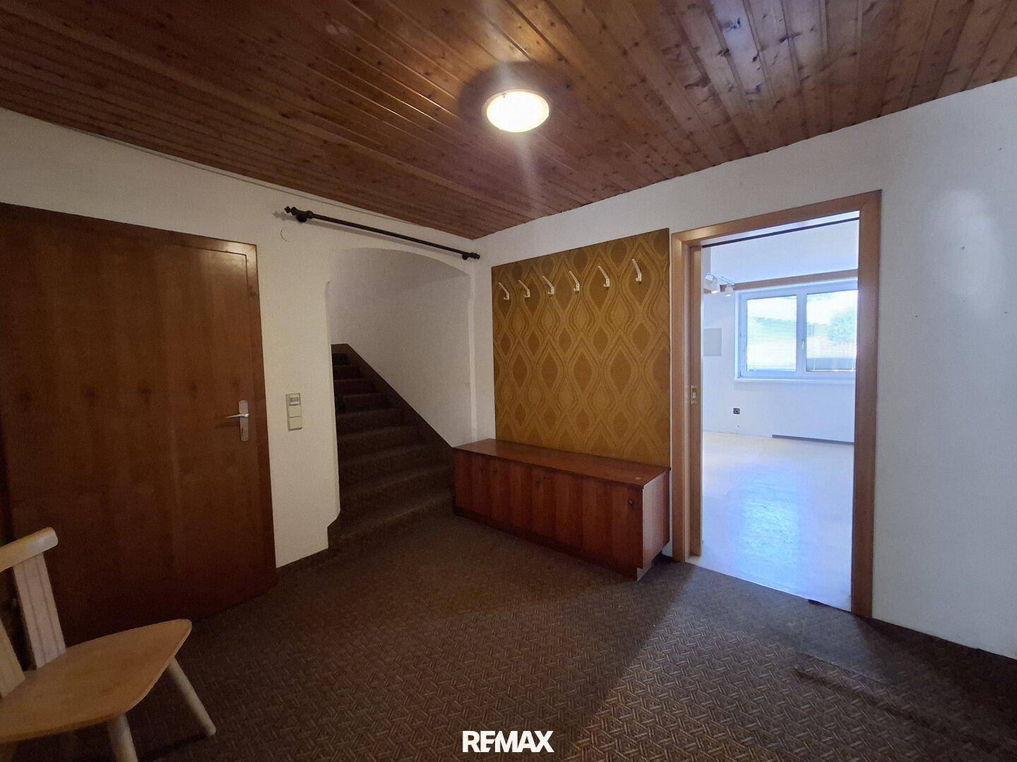 Geräumiger Flur mit Holzdecke, Teppichboden und Treppenaufgang.