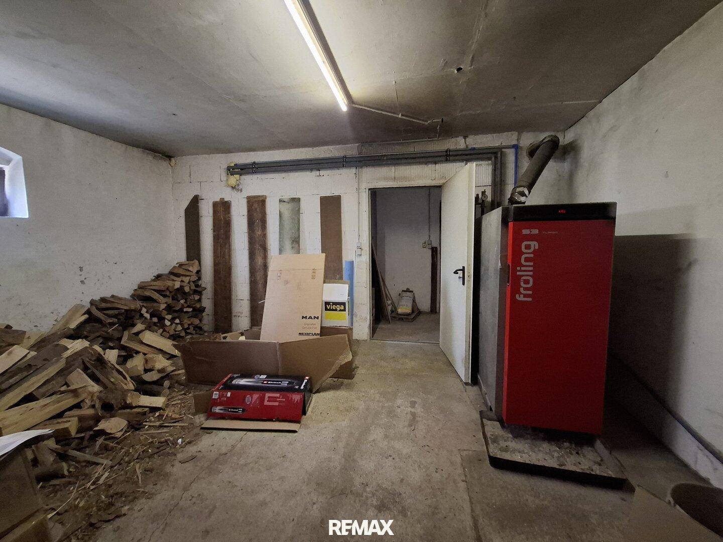 Heizraum mit Holzscheiten und einem modernen Heizkessel.