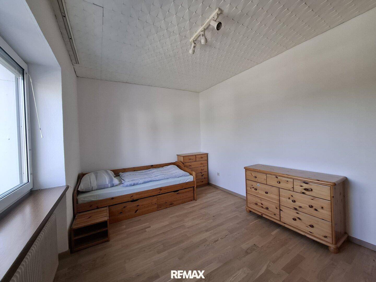 Gemütliches Schlafzimmer mit Einzelbett, Holzmöbeln und Parkettboden.