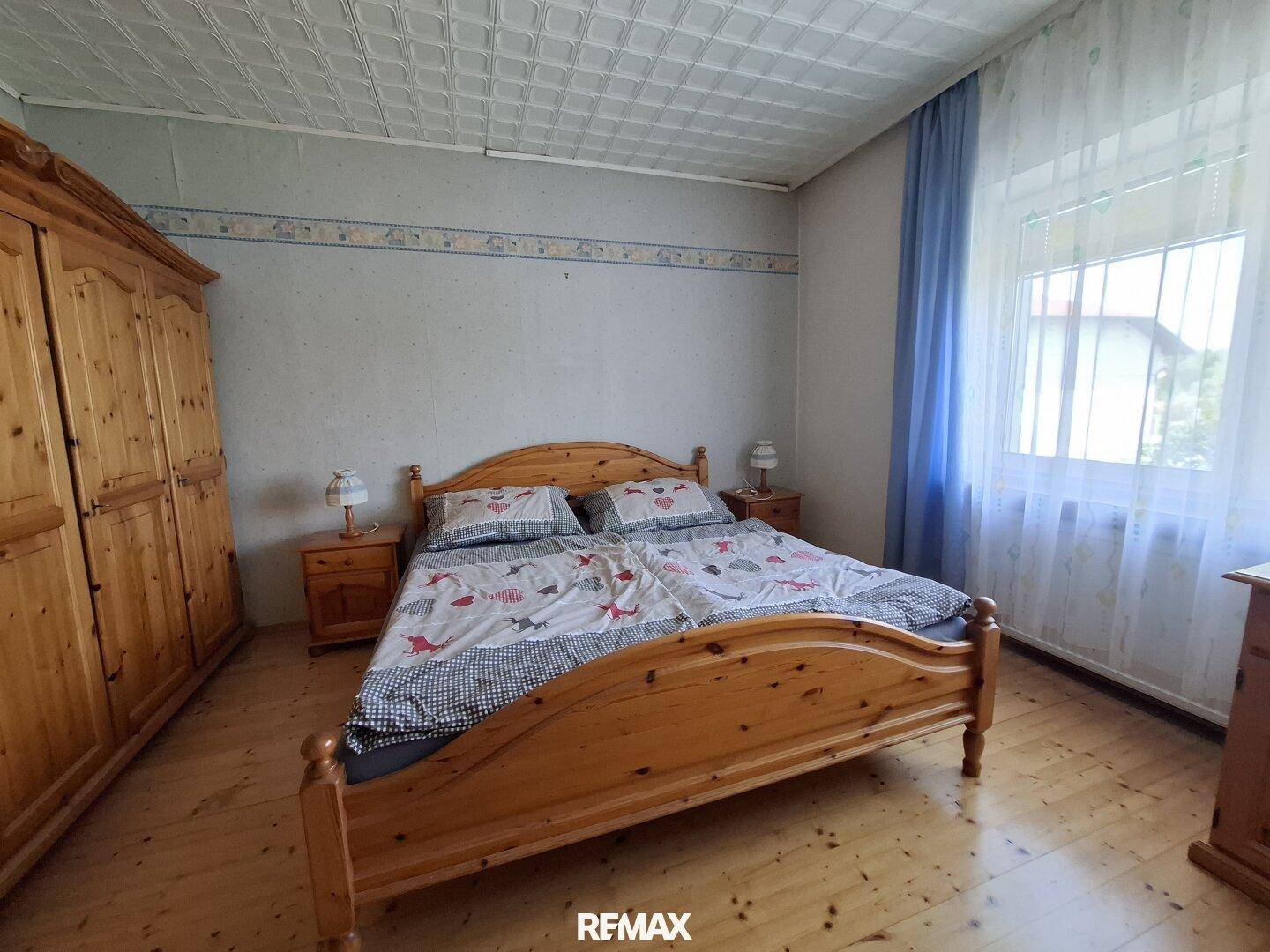 Schlafzimmer mit Doppelbett, großem Holzschrank und Parkettboden.