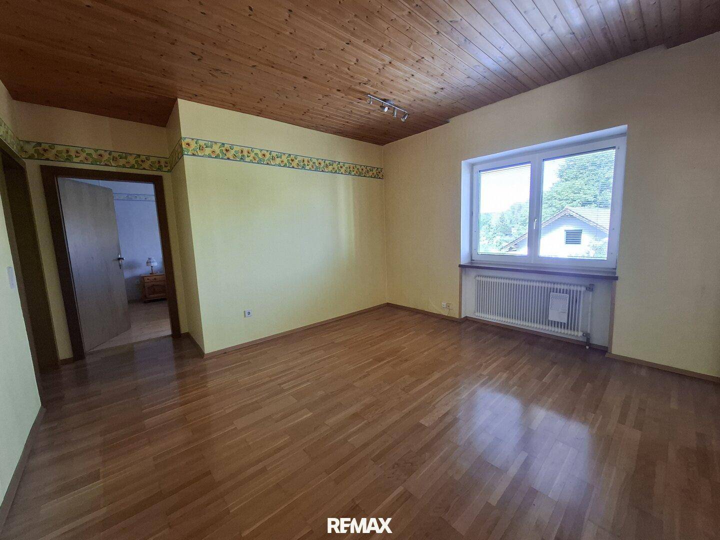 Schlafzimmer mit Holzdecke, Parkettboden und dekorativer Tapetenbordüre.