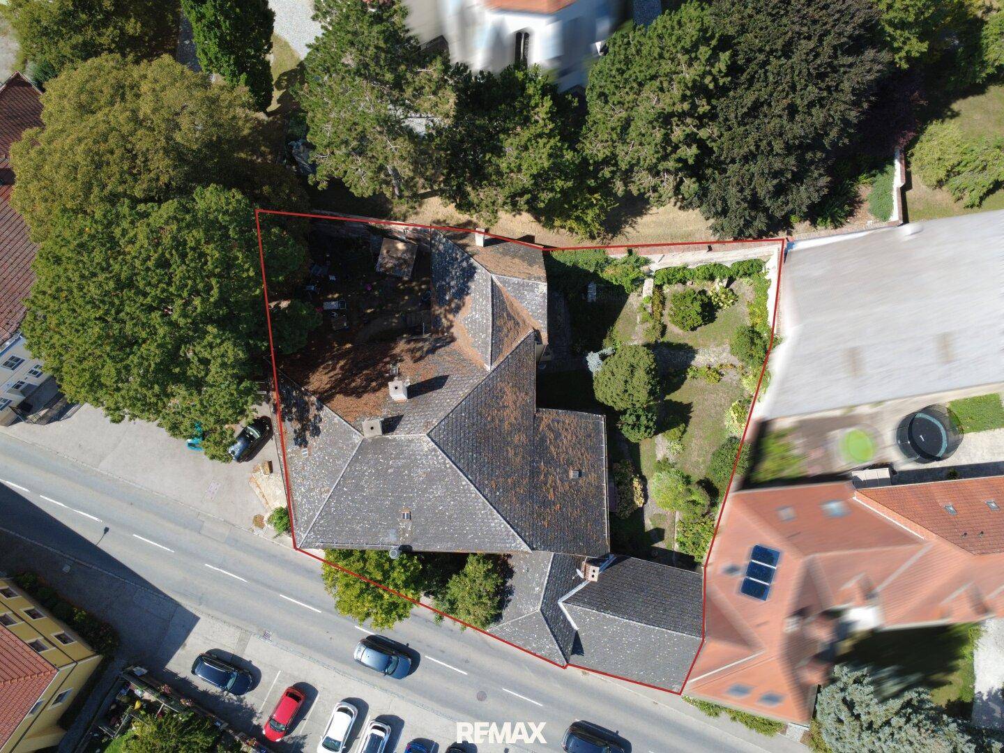 Luftaufnahme des Anwesens mit umliegendem Garten und angrenzender Straße, umrandet in Rot.