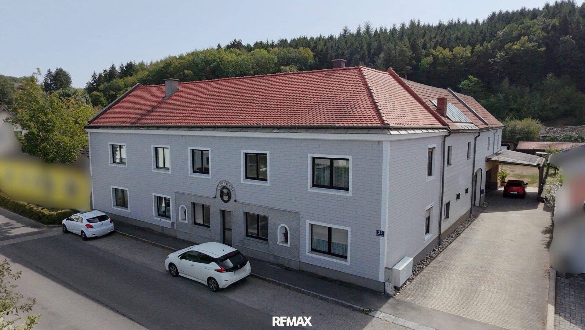 Ansicht eines traditionellen Gebäudes mit rotem Ziegeldach und gepflegter Fassade.