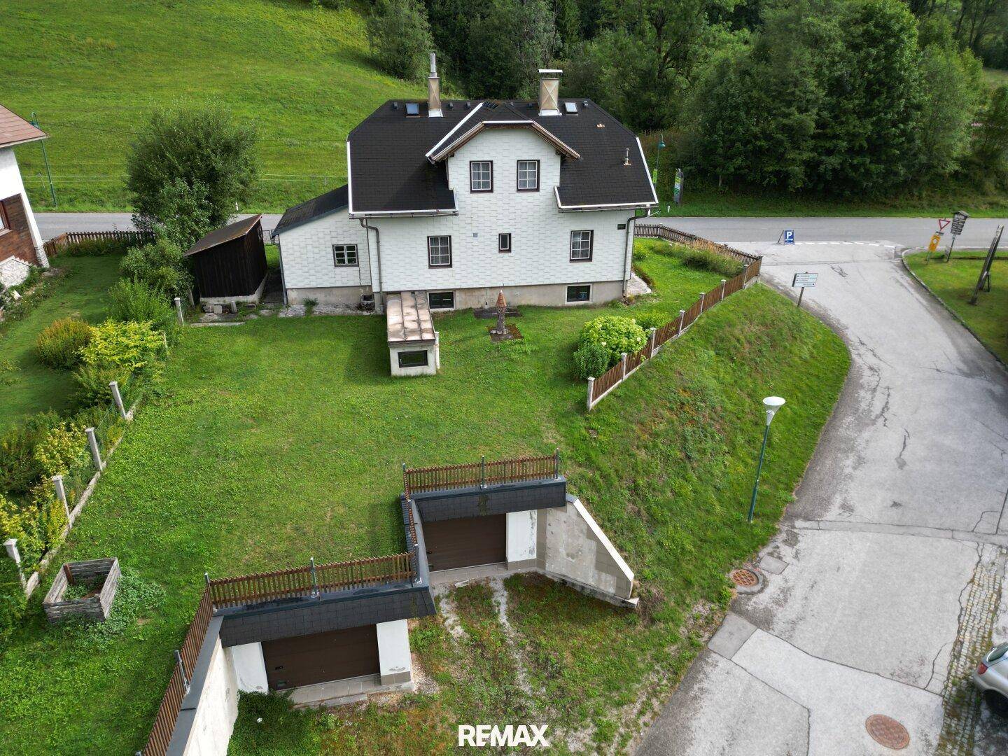 Luftaufnahme des Hauses mit großem Garten, Zufahrt und zwei Garagen.