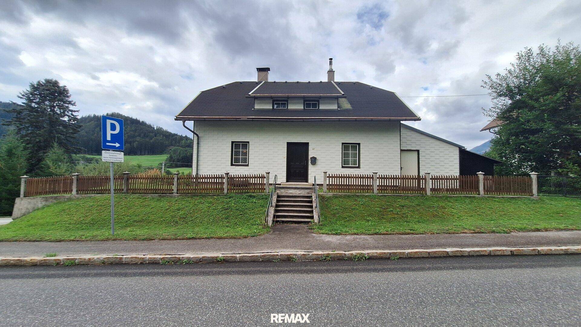 Vorderansicht des Hauses von der Straße mit Zaun und Vorgarten.