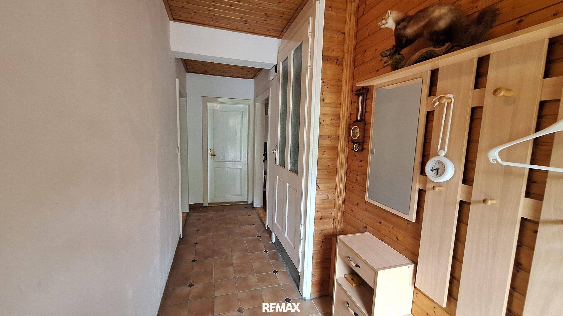 Flur mit Holzvertäfelung an der Wand und Terrakotta-Fliesenboden.
