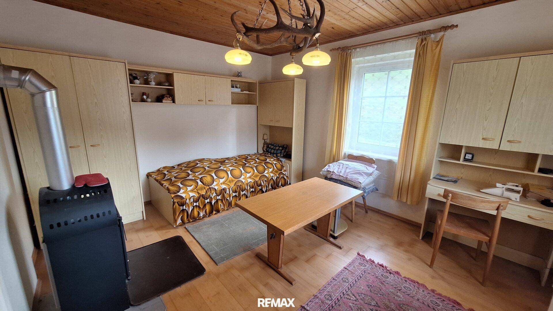 Schlafzimmer mit Kaminofen, Holzdecke und Einbauschränken.