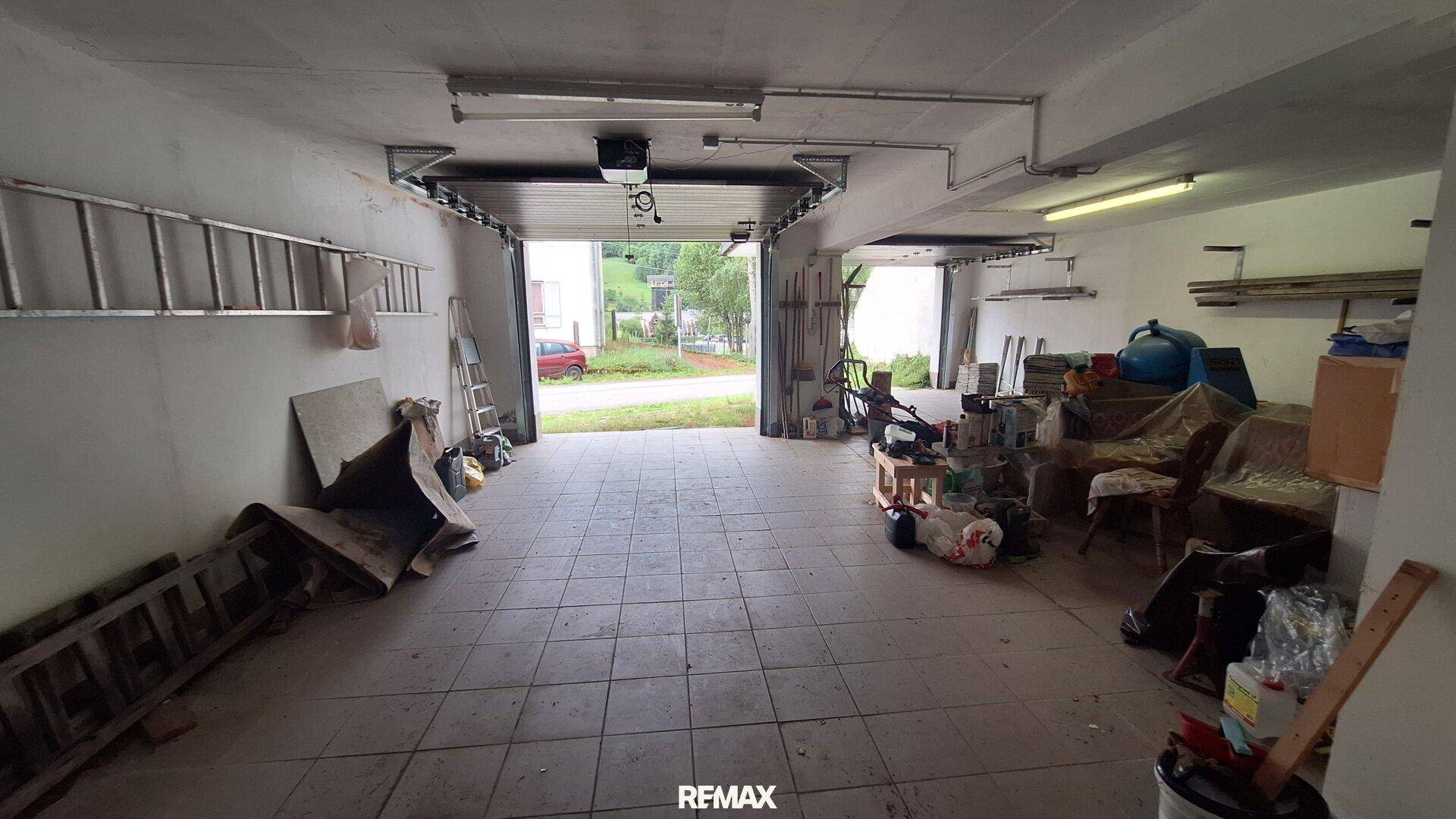 Geräumige Garage mit Fliesenboden und Blick nach draußen.