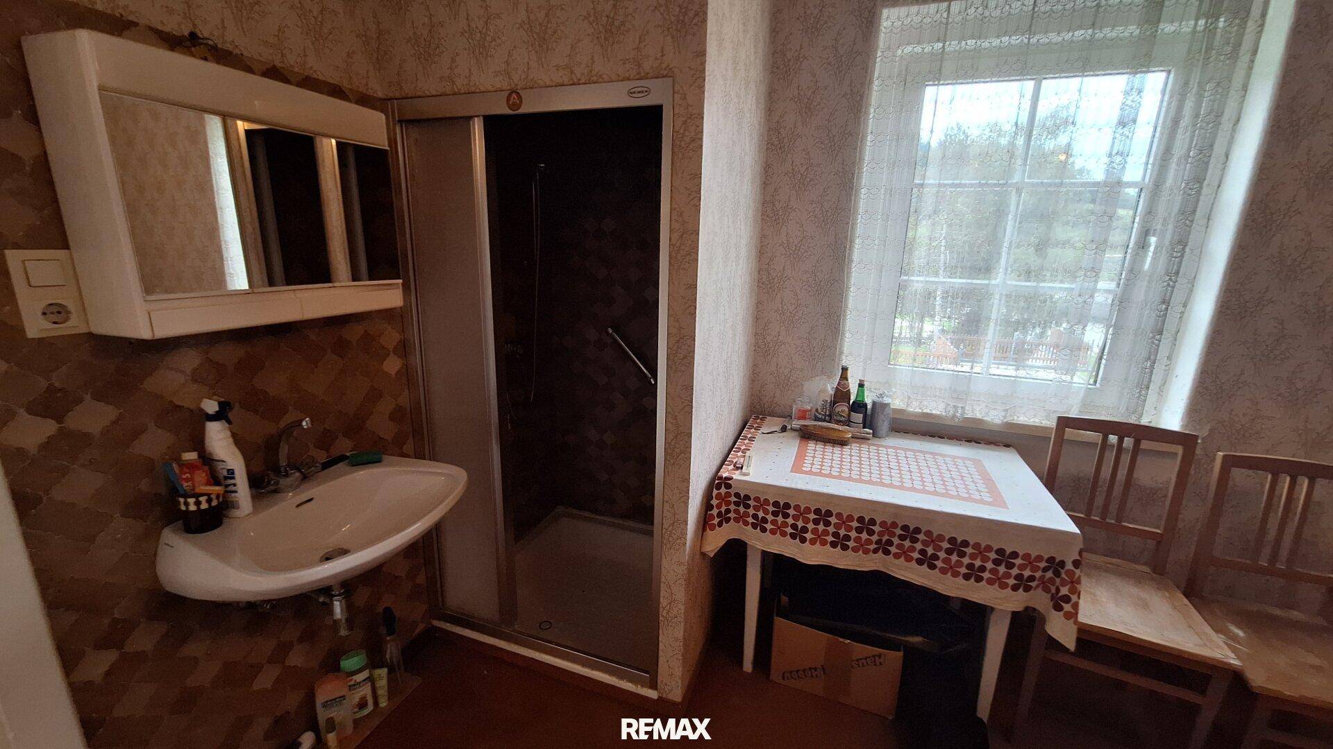 Badezimmer mit Duschkabine, Waschbecken und Fenster für Tageslicht.